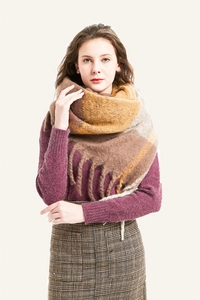 Detail of thick brown plaid scarf with long tassels draped over a burgundy sweater
