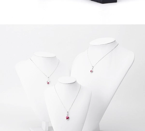 Three white busts displaying silver necklaces with pink ruby pendants in tiered layout