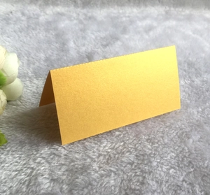 Close-up of golden laser-cut butterfly place card standing on a white plush surface