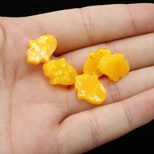 Detailed macro view of five yellow glitter Hamsa resin pendants held in a person's palm