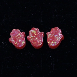 Detail of red resin Hamsa hand beads with golden flakes on black velvet background