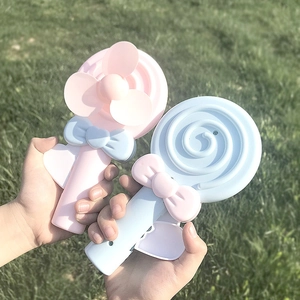 Close-up of lollipop-shaped manual hand fans in pink and blue held over a green lawn