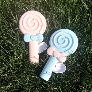 Close-up of pink and blue lollipop-shaped manual hand pressure fans on green grass