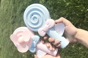 Close-up of hand-held cartoon lollipop fans in blue and pink for children outdoors