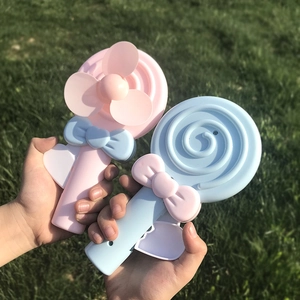 Detailed view of pink and blue lollipop-shaped hand-press fans on green grass