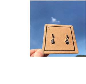 Detail of luxury evil eye earrings with blue crystals held against a clear blue sky