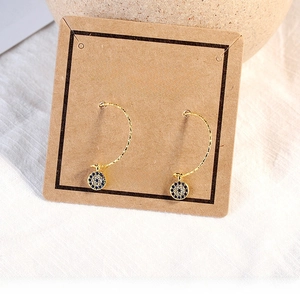 Detail of luxury gold evil eye earrings with blue and white zircons on display card