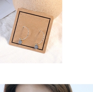 Detail of luxury evil eye earrings with blue and white crystals on textured stone