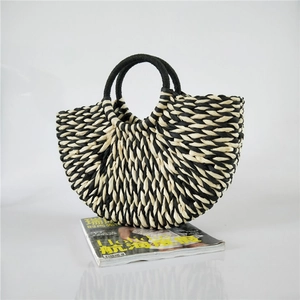 Detail of a black and white striped woven half-moon tote bag with round handles