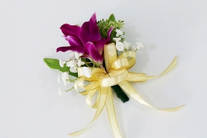 Detalle de boutonnière de orquídea púrpura artificial con cinta de seda dorada para bodas