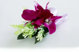 Detail of purple artificial orchid boutonniere with silk ribbons and white foam accents