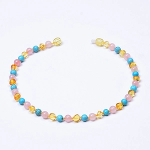 Collier bébé en ambre naturel et quartz rose avec perles turquoise sur fond blanc