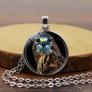 Close-up of eagle head glass pendant necklace on a natural wooden display base