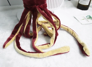 Detailed close-up of soft plush octopus tentacles in dark red and cream colors