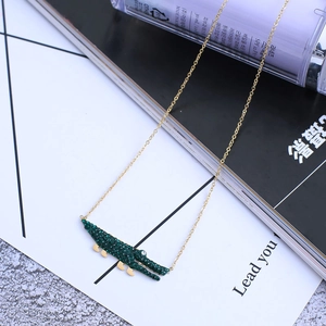 Gros plan détaillé du collier pendentif crocodile en strass vert et chaîne dorée