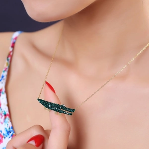 Détail d'un pendentif crocodile en strass vert sur une chaîne dorée élégante