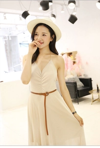 Detail of slim brown leather belt on a pleated beige V-neck dress for a soft casual look