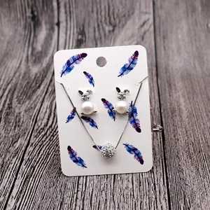 Detail of bunny stud earrings and necklace set with pearls and rhinestones on feather card