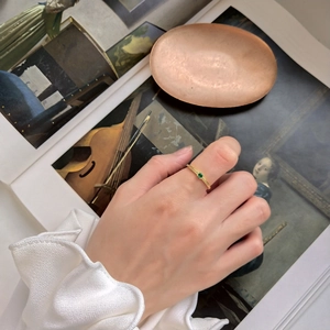 Close-up of gold spiral texture band ring with round green gemstone on finger
