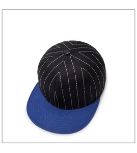 Detail view of a snapback baseball cap featuring a black crown with blue visor and white stitching