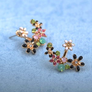Detailed macro view of gold-plated floral stud earrings with multi-color rhinestones