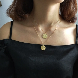 Close-up of double-layered gold coin necklaces with character relief pendants