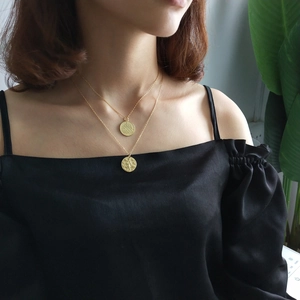 Close-up of double-layer gold coin necklace with Sagittarius engraving worn by model