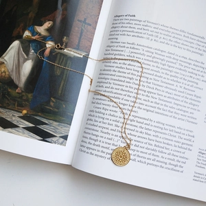 Detail of S925 sterling silver gold coin necklace on an artistic art book background