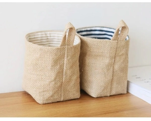 Close-up of small jute storage bags with striped lining and woven handles on wood table