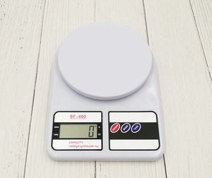 Top view of white SF-400 digital kitchen scale with 10kg capacity on wooden desk