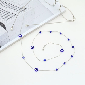 Silver evil eye glasses chain with blue beads and charms on a white magazine background
