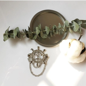 Détail d'une broche gouvernail argentée style nautique avec ancre, cristaux et chaînes