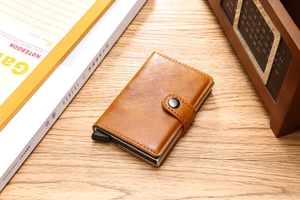 Brown PU leather automatic pop-up wallet with metal card holder on a wooden desk