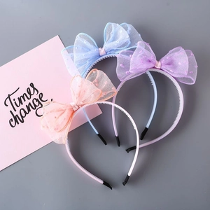 Detailed view of three mesh bow headbands in blue, pink, and purple with polka dot patterns