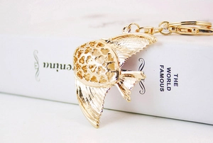 Macro detail of golden metal tropical fish keychain featuring intricate hollow-out wings