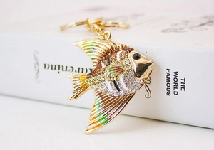 Close-up of golden tropical fish keychain with colorful rhinestones on book background