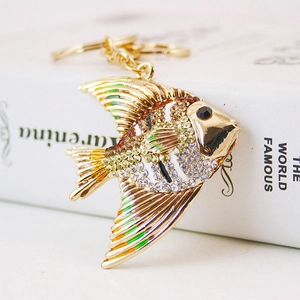 Golden tropical fish keychain with sparkling rhinestones on a decorative book background