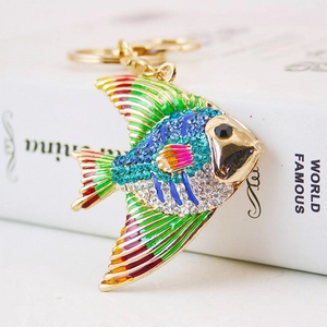 Golden fish keychain with colorful enamel and crystal rhinestones on a book background