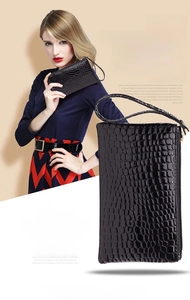 Detail of black crocodile embossed wristlet pouch with metal zipper and leather strap