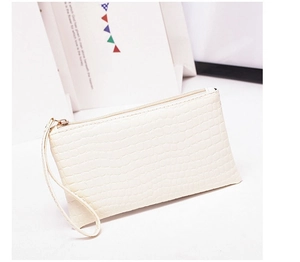 Detail of white crocodile pattern wristlet pouch with golden zipper and leather strap