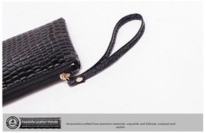Detail of black crocodile texture clutch bag with wrist strap and golden zipper