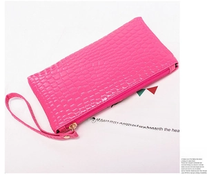 Detailed close-up of rose red crocodile embossed wristlet bag with zipper and strap