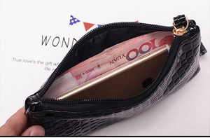 Detail view of crocodile textured black wallet showing interior capacity for cash and phone