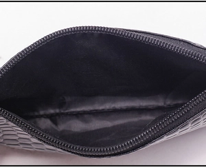 Detailed macro view of black crocodile pattern wristlet with zipper and fabric lining