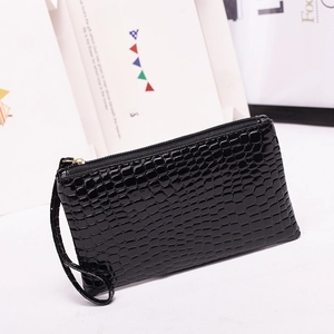 Fashionable black faux crocodile leather clutch bag with golden zipper on a white stage