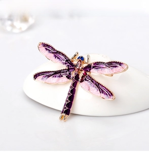Macro shot of elegant purple enamel wings and golden finish on a dragonfly brooch