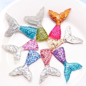 Glittering resin mermaid tail craft charms in various gradient colors on white tray