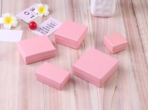 Pink textured jewelry gift boxes in various sizes displayed on a wooden surface