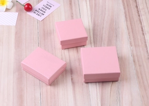 Detailed top view of three pink matte gift boxes for jewelry on a wooden background