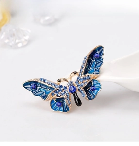 Detailed view of blue enamel butterfly brooch with rhinestones on a white spoon